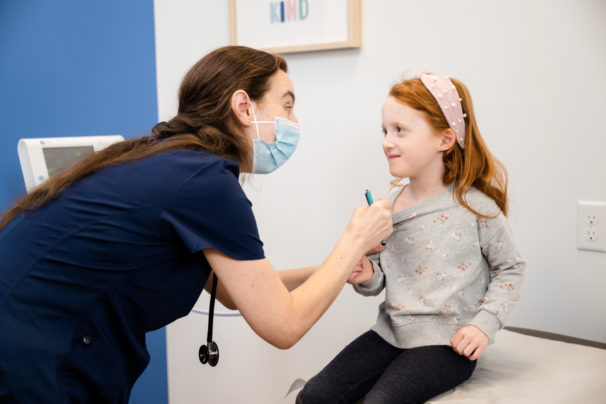 A Care+ nurse gently examining a young girl in an exam room at the North OKC clinic